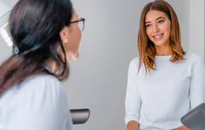 Gynecologist talking with young female patient during medical consultation in modern clinic - stock photo